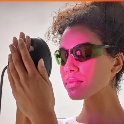 Woman wearing protective glasses during red light therapy treatment session.