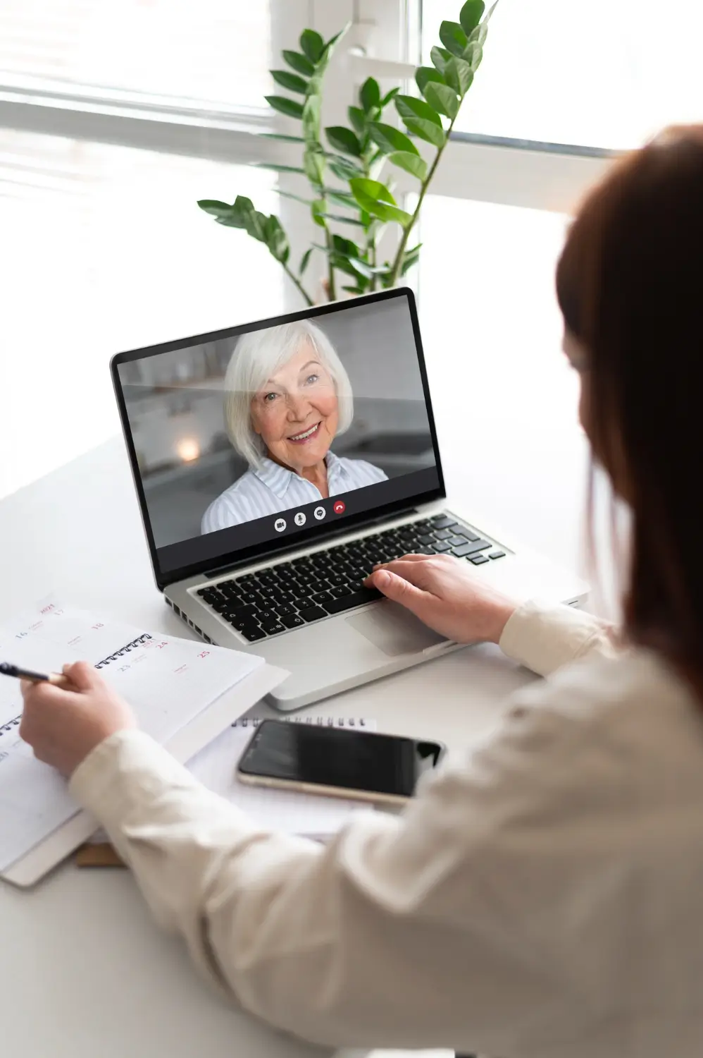 Person in white shirt having friendly video call with older woman.